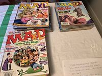Two stacks of Mad magazines displayed on a table showing colorful cartoon covers, some wear visible.