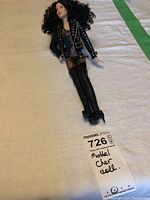 Photo of Mattel Cher collector doll laying down showing the full outfit and curly hair.