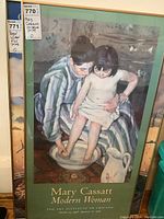 Clear front view of the framed Mary Cassatt print showing a woman bathing a child titled 'Modern Woman.' The frame is wood with green inner matting.