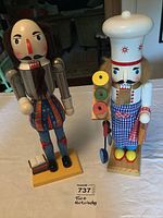 Two wooden nutcrackers, a soldier and a chef, standing next to each other on a table.