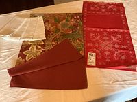 Two table runners and four napkins laid flat on a white surface, showing the multicolored autumnal table runner and plain white napkins.