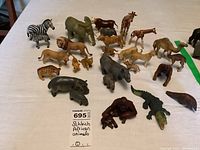 Top down view of approximately 30 Schleich African animal figures arranged on white surface including lions, elephants, giraffes, zebras, tigers, and more.