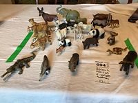 Photo showing approximately 26 African species animal figurines from Schleich and Ertl brands arranged on white cloth.