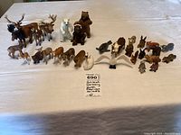 Overall view of approximately 30 Schleich animal figures arranged on a table showing moose, bears, deer, and smaller mammals