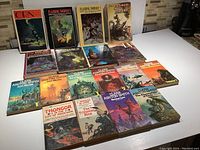 Eighteen books arranged in three rows on white surface