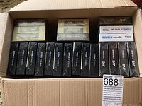 Box showing multiple sealed VHS tapes including JVC, Konica Super SR T120, and TDK T-120EHG.