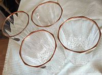 Top down view of four clear leaded crystal tumblers with 24K gold rims showing intricate cuts and weighted bottoms.