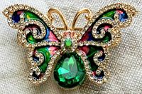 Close-up of butterfly brooch showing detailed rhinestones and colorful enamel decoration.