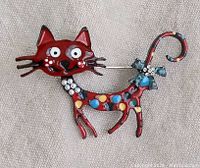 Front view of a colorful enamel Krazy-Kat style cat brooch with rhinestone collar.