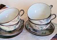 Group photo of 5 porcelain teacups stacked on matching saucers, showing detailed dragon designs and color scheme.