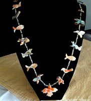 Full view of Zuni fetish necklace displayed on black bust showing multiple hand-carved animal pendants spaced with beads and a larger bird pendant at center