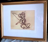 Framed print with a sketch drawing of Tinkerbell sitting and smiling with wings. Gold frame with white matting.