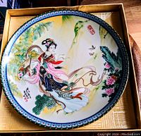 Collector's hand-painted ceramic plate featuring a traditional Chinese woman figure with floral details, framed in original box