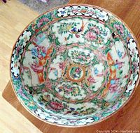Top-down view of vintage Chinese porcelain bowl with intricate famille-rose decoration showing floral motifs and birds.