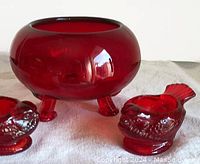 Side view close-up of cranberry glass flower bowl and bird-shaped candle holders