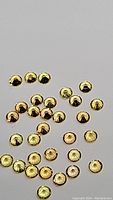 Photo showing loose small round golden yellow sapphires with diamond cut faceting, scattered on a flat surface.