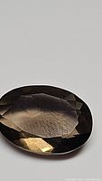 Close-up front view of the oval cut smokey quartz gemstone showing its facets and color.