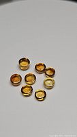 Eight round cabochon golden citrine gemstones on white background, showing color and shape.