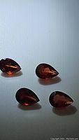 Four pear cut cherry red Mozambique garnets positioned on a white background showing facets and color