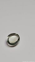 Oval cabochon cut natural green amethyst gemstone with smooth domed surface and teal green color, shown from one angle.