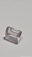 Close-up of 3.72 carat natural rose quartz emerald cut gemstone showing light pink transparency and emerald cut shape.