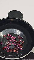 Top view of round cabochon purple pink rhodolite garnet stones in a black dish showing color and cut