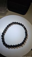 Top view of the circular stretchy bracelet showing round silver sheen obsidian beads with natural patterns.