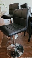 Two black vinyl bar stools showing cushioned seats and backrests beside counter.