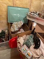 Boxes and totes with wrapped fragile items, Christmas decorations, and ceramics including black ceramic cat and tall vase