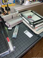 Overview of crafting supplies including cutting mats, rulers, rotary cutter, and caddy with paint brushes on table.