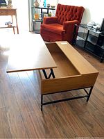 Side view of the coffee table with the left side top panel lifted, showing the interior storage compartment and metal hinges.