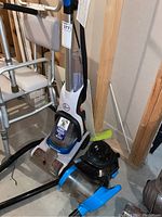 Hoover Power Dash Pet carpet cleaner and Bissell power vacuum cleaner placed on floor showing front view with hose attachments