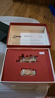 Open original box displaying red foam insert with cutouts for 2 locomotives and tenders, showing instruction sheet inside box lid.