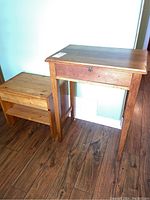 View showing pair of pine side tables, one smaller nightstand and one larger side table, positioned next to each other on a hardwood floor.
