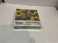 Sealed box of a 1000 piece jigsaw puzzle with an image of birds on sunflowers.