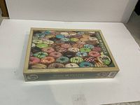 Image of closed rectangular puzzle box with colorful donut assortment on cover, labeled 1000 piece puzzle by Cobble Hill.