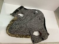 Small black and white herringbone patterned dog coat with attached hood and faux fur border at bottom, velcro closure on the front.