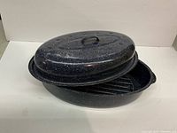 Blue enamel steel roasting pan with matching lid and wire rack inside.