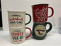Four mugs displayed stacked and side by side on white background. Two Christmas mugs with recipes stacked on the left; red 'Comfort & Joy' mug stacked above green 'Life's Better at the Lake' mug on right.