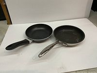 Top view of two frying pans showing cooking surfaces and handles.