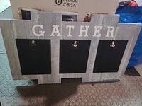 Front view of wooden picture frame with 'GATHER' text and three black picture clips with gold metal clasps