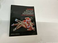 Photo of the textbook cover showing the title, author name, and a graphic of gymnasts.