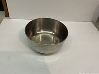 Single medium-sized stainless steel mixing bowl on a white surface, showing the outside and inside of the bowl with a reflective metallic finish.
