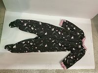 Single black long sleeve footed baby onesie with pink cuffs and white and pink pattern, laid flat for display