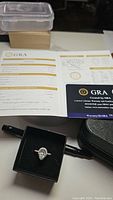 Ring in black presentation box alongside GRA certificate paperwork and warranty card