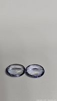 Front view of two oval cut tanzanite gemstones placed side by side showing their color and clarity.