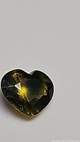 Close-up photo of the heart-shaped multicolored sapphire showing the yellow-green-blue bi-color effect.