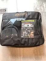 Packed Coverado car seat covers in black with visible installation guide inside clear plastic packaging.