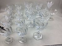 Full set of 22 vintage crystal glasses featuring swirl design and hexagonal bases photographed on a white surface.