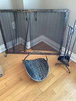Full view of the vintage iron fireplace accessories grouped together including fire screen, coal scuttle, and tool set.